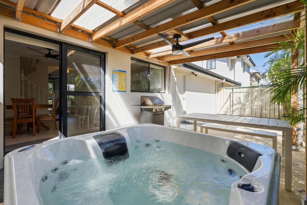 a large bath tub sitting on a patio at Hawks Nest Hideaway | Spa, BBQ, Bikes & Pool Table in Hawks Nest