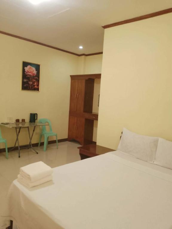 a bedroom with a bed and a table with chairs at Hidden Valley Guest House in Malapascua Island