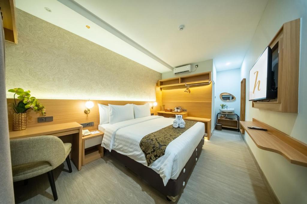 a hotel room with a bed and a desk at Horison IJ Kudus in Kudus