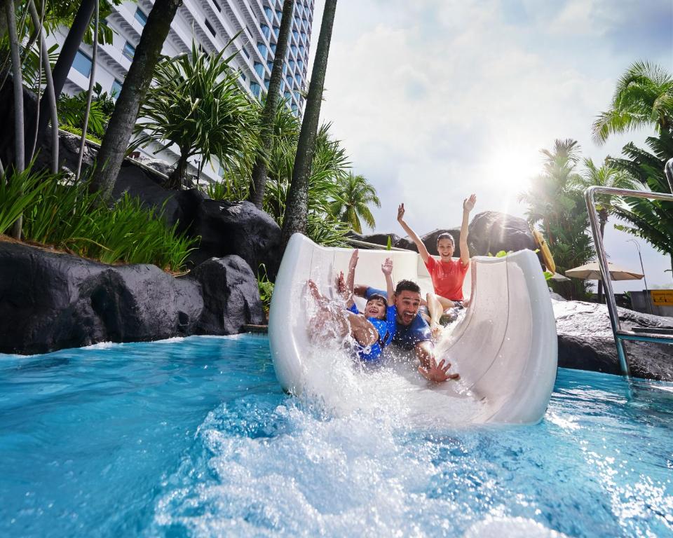 a group of children riding a water slide at a resort at Hilton Kuala Lumpur in Kuala Lumpur