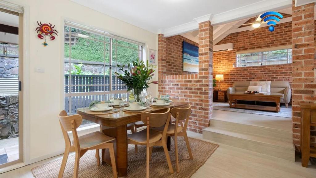 a dining room with a wooden table and chairs at Bombo Blue in Kiama