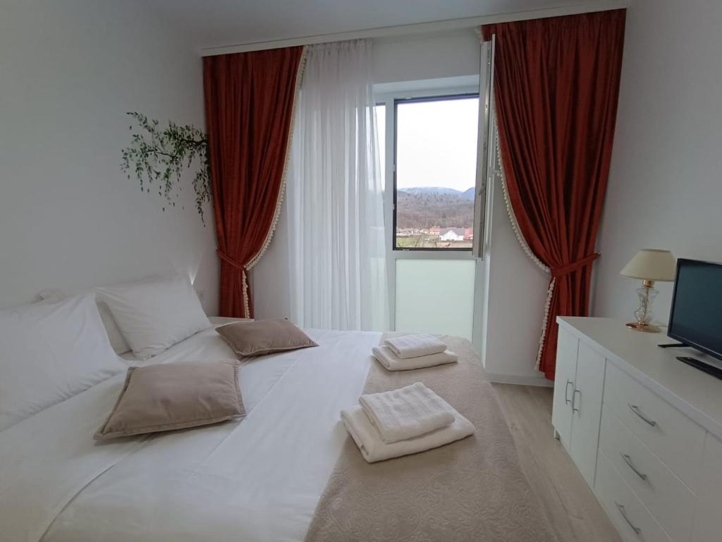 a bedroom with a large white bed with red curtains at Cazare Rasnov cu vedere spre Postavaru in Râşnov