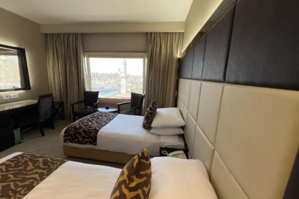 a hotel room with two beds and a desk at El Mohandseen Cairo Hotel in Cairo