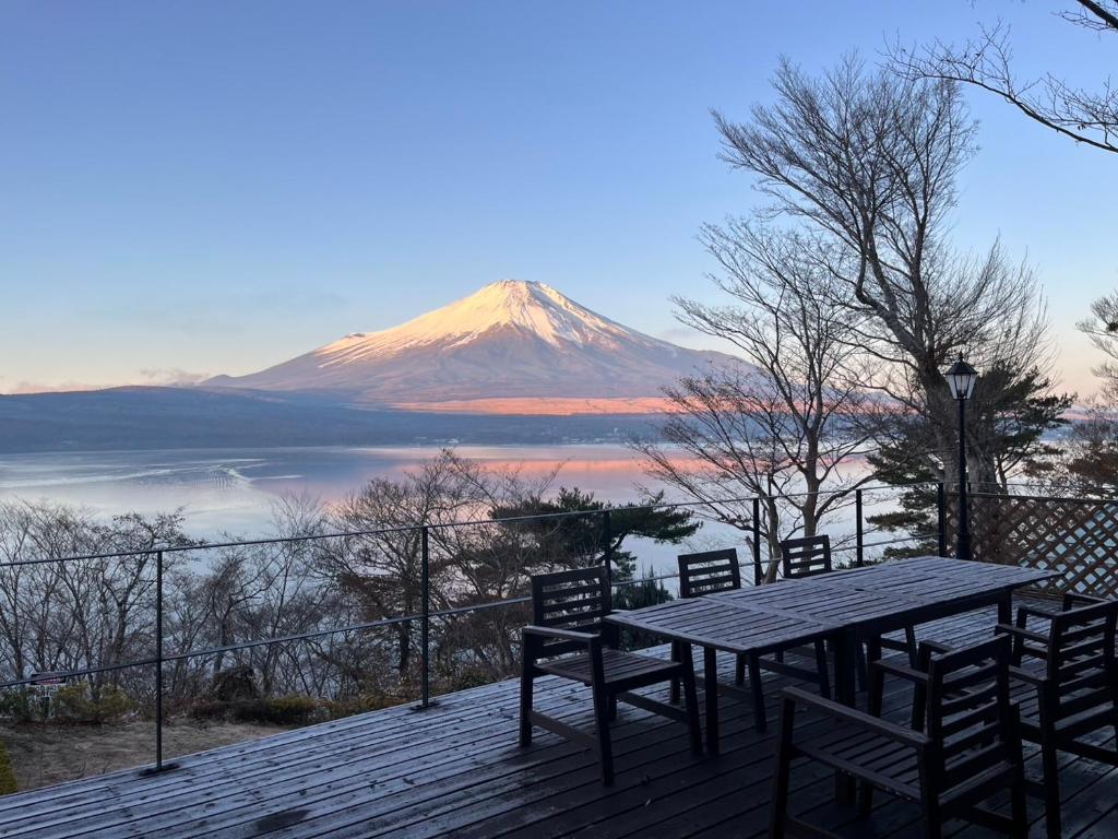 a table and chairs on a deck with a mountain at Buckeye House by the lake in Yamanakako