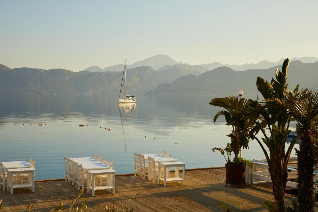 a boat in the water with tables and chairs on a dock at Selimiye Sardunya Hotel & Restaurant in Marmaris