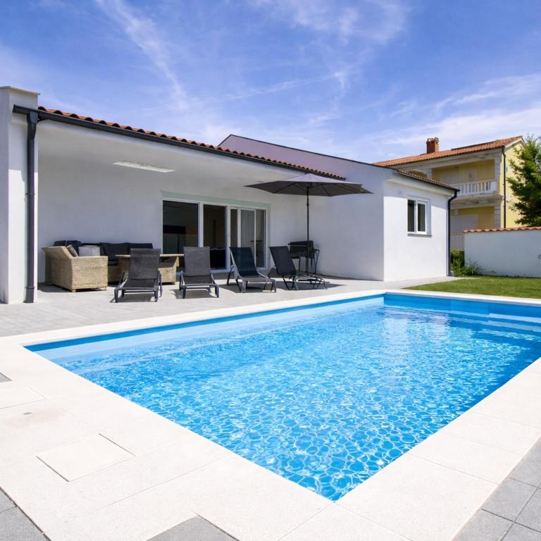 a swimming pool in front of a house at More i Sol Rab Pool House in Rab