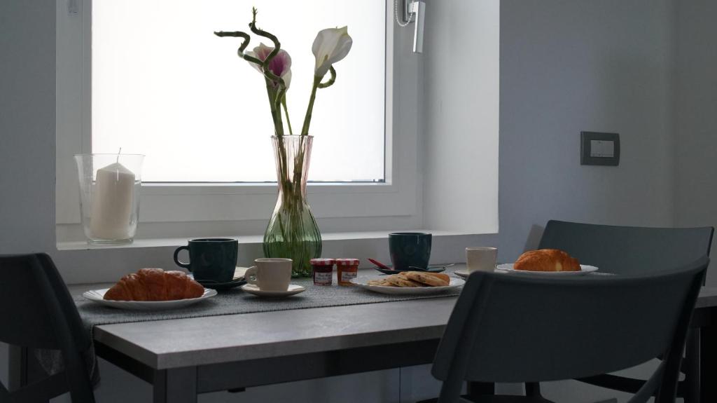 a table with plates of food and a vase with flowers at A Casa Mia 2.0 in Saronno