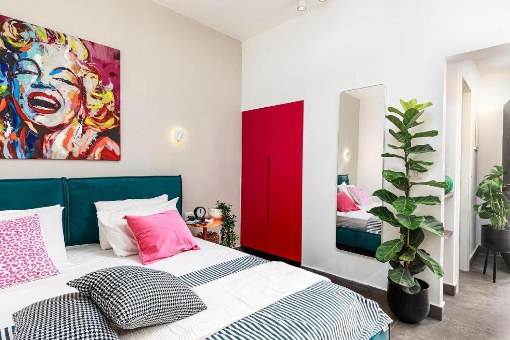 a bedroom with a bed and a painting on the wall at דירת סטודיו שקטה עם גקוזי בלב ראשלצ in Rishon LeẔiyyon