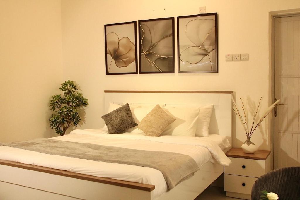 a bedroom with a bed with four pictures on the wall at رخاء للغرف الفندقية in Firq