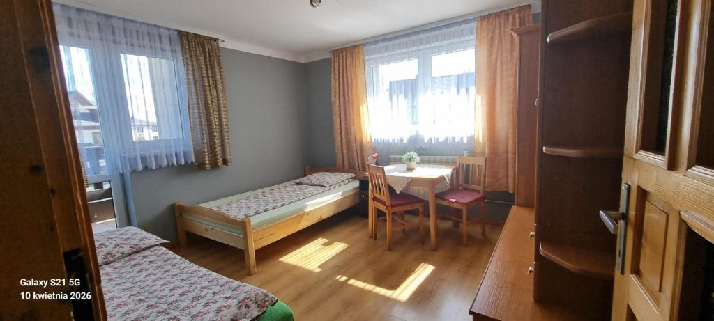 a room with two beds and a table and a dining room at Noclegi u Danuty in Groń
