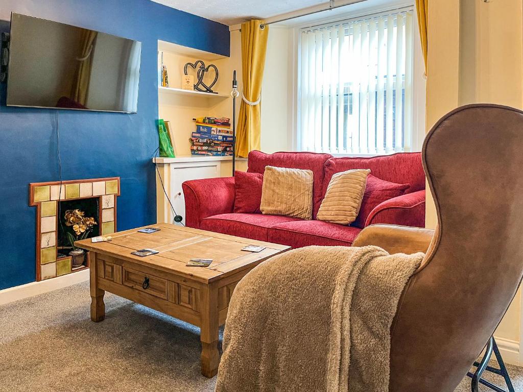 a living room with a red couch and a coffee table at North Lakes Town House in Penrith