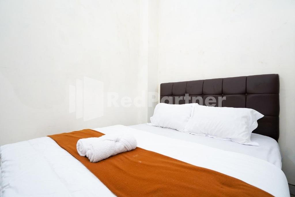 a white bed with two towels laying on it at Griya Poerwoto Syariah near Pasar Klewer Solo RedPartner in Solo