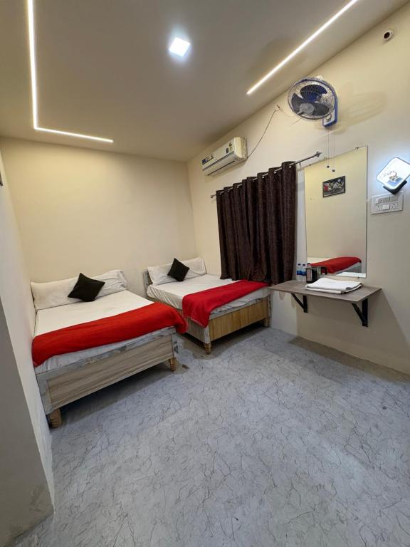 a small room with two beds and a desk at Hotel Shivay Deluxe in Nagpur