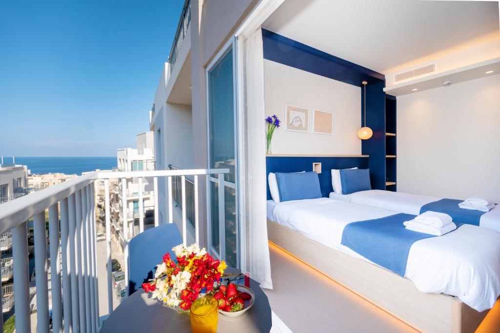 a bedroom with two beds and a balcony with the ocean at Atlantis Lodge in Marsalforn