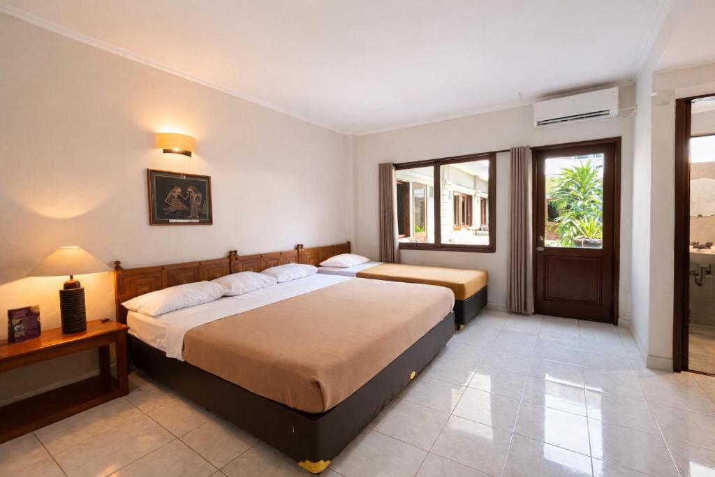 a bedroom with two beds and a window at Hotel Winotosastro Garden in Yogyakarta