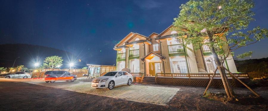 a white car parked in front of a building at Red Windmill Pension in Jeju