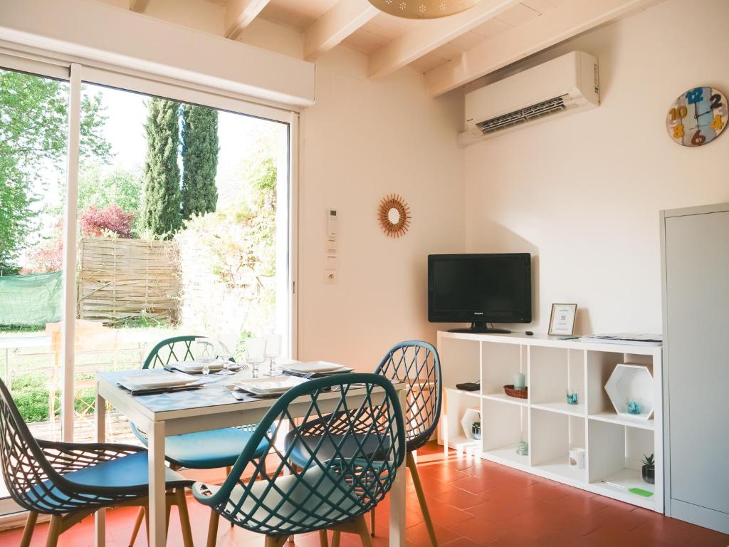 a dining room with a table and chairs and a tv at L'ESCAPADE T3 avec terrasse privative in Lussac-les-Châteaux