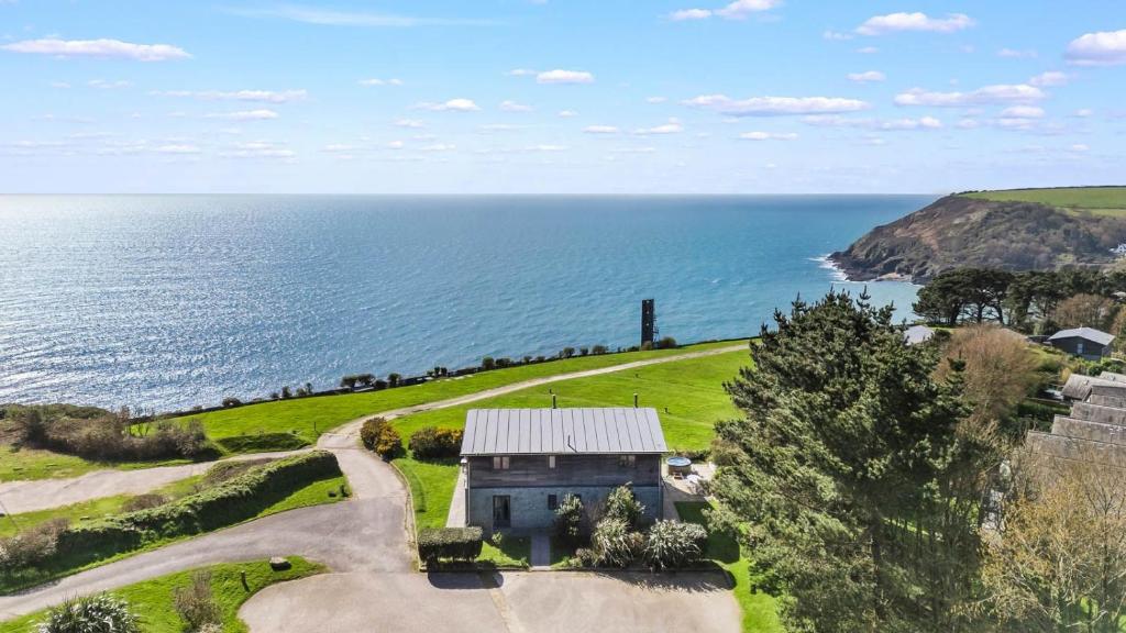 an aerial view of a house on a hill next to the ocean at House 43 in Looe