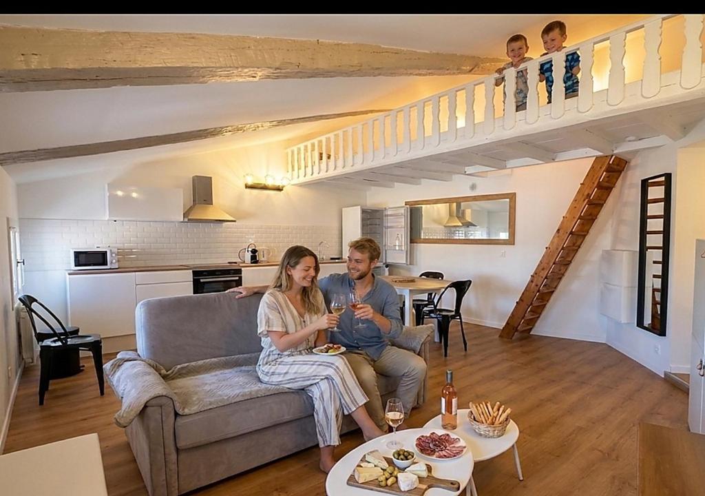 a man and woman sitting on a couch in a living room at Grand studio 31 m2 plus mezzanine centre ville grasse in Grasse
