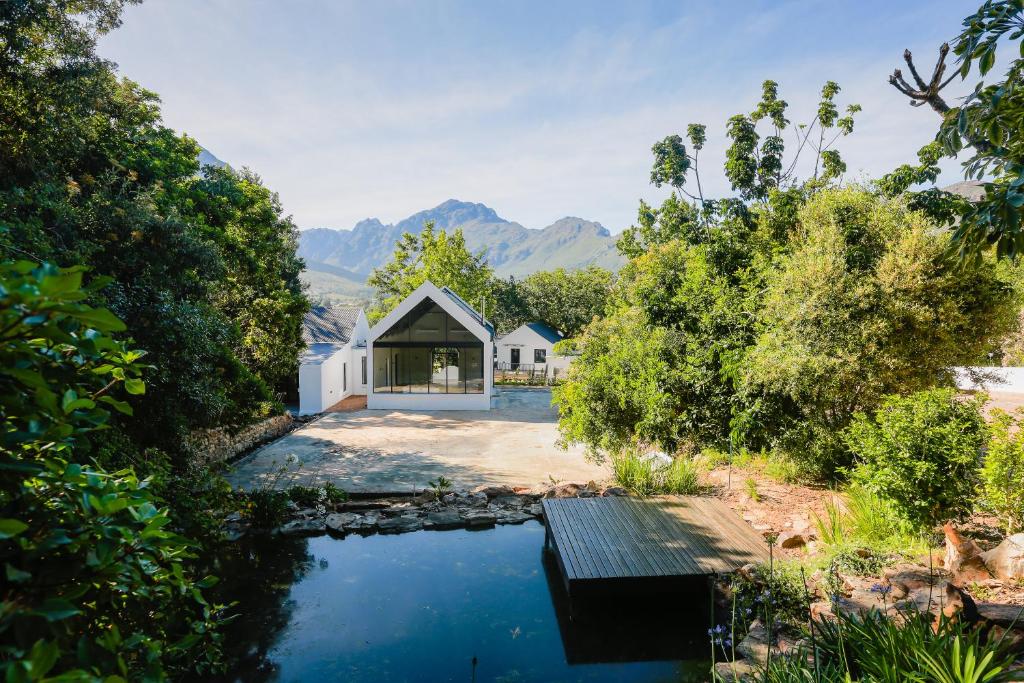ein Haus mit einem Teich und Bergen im Hintergrund in der Unterkunft Hemelberg in Stellenbosch