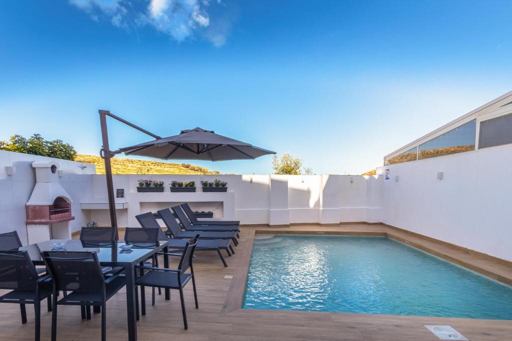 a patio with a table and chairs next to a swimming pool at Dar Sara Holiday Home in Victoria