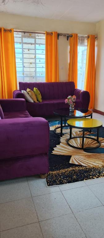 a living room with purple couches and a table at Chaka homes 2 bedroom in Kiganjo