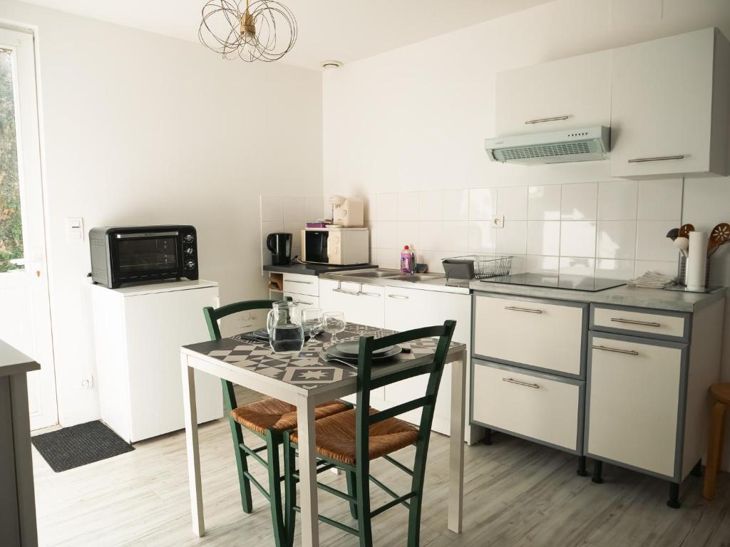 a kitchen with a table and two chairs in it at LE REPOS DU VOYAGEUR T3 45 m2 tout confort in Lussac-les-Châteaux