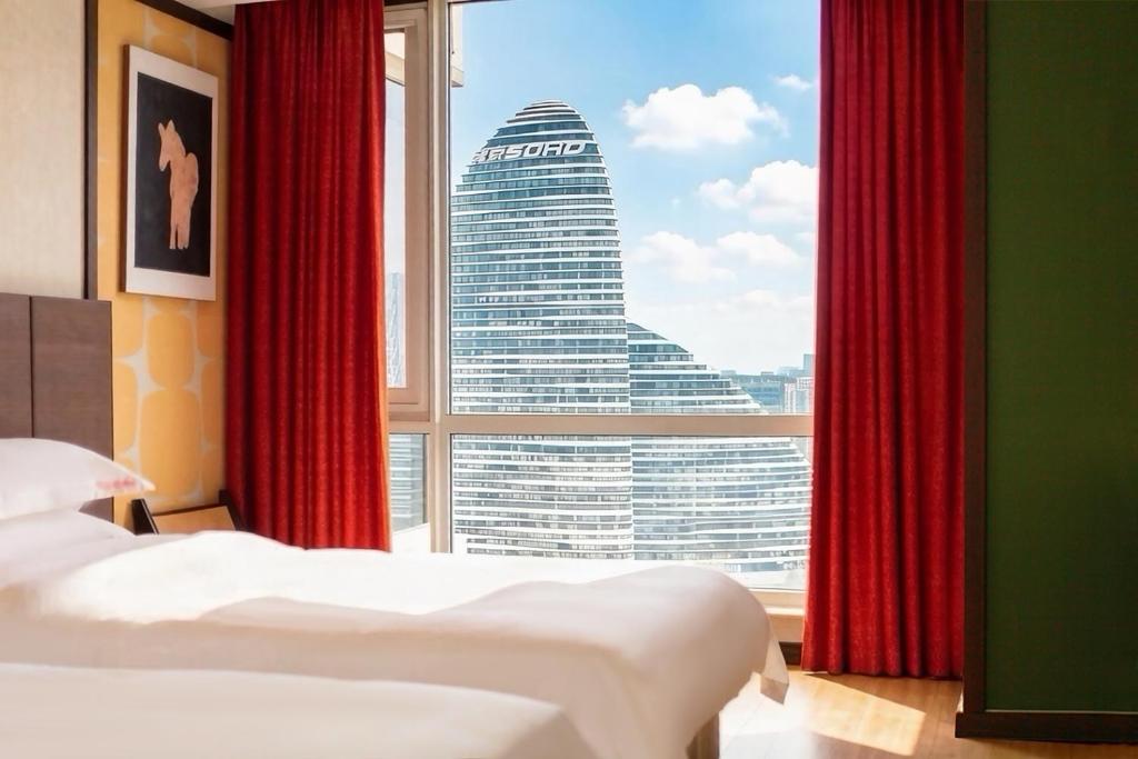 a hotel room with two beds and a large window at Pumpkin Hotel in Beijing