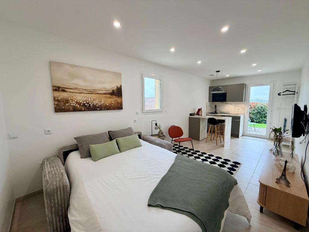 a living room with a large white bed and a kitchen at Cosy studio with garden in Chevry