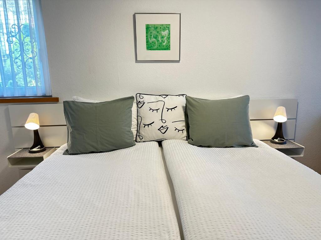 a bedroom with a bed with two pillows and two lamps at Studio Breiti I eigener Eingang l self check in l nähe Basel in Pratteln