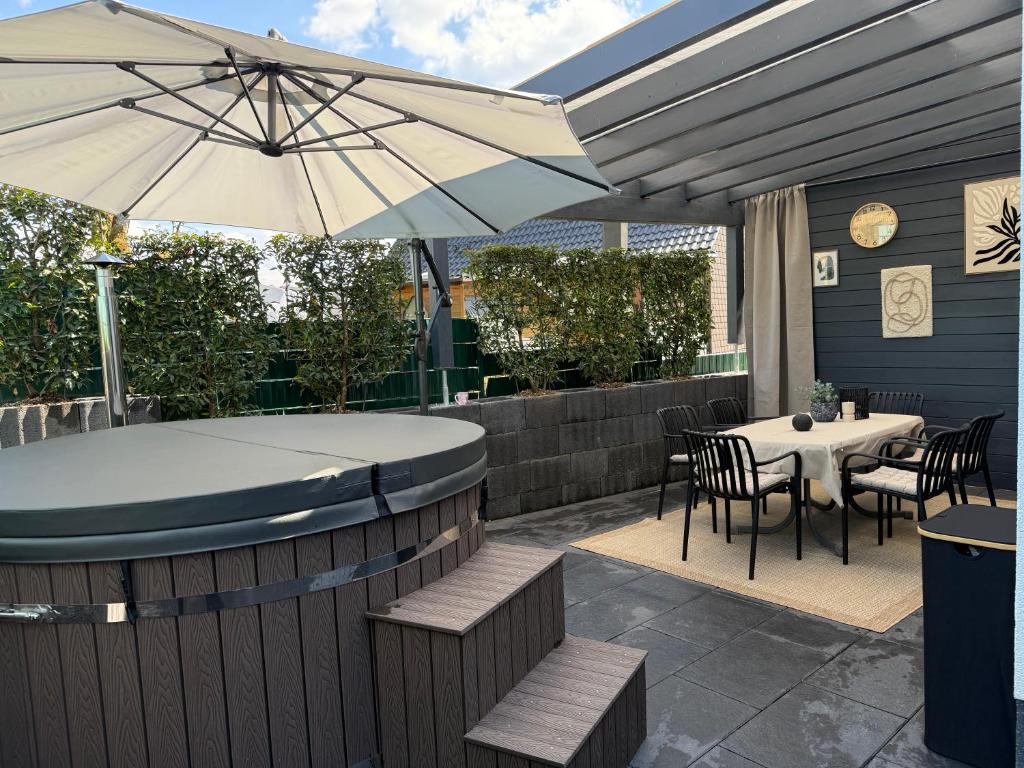 a patio with an umbrella and a table and chairs at Sauerland Wellness Apartment mit Sauna und Jacuzzi in Olpe