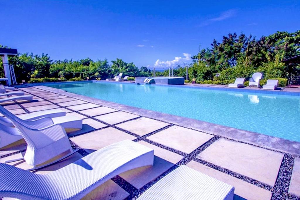 a swimming pool with lounge chairs and a swimming pool at Alta Bohol Resort powered by Cocotel in Tagbilaran City