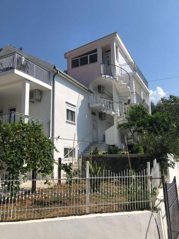 a white building with a fence in front of it at Viola Apartmans Lux in Šušanj