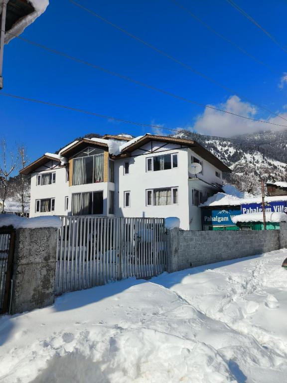 a white house with a fence in the snow at Hotel Pahalgam Villas in Pahalgām