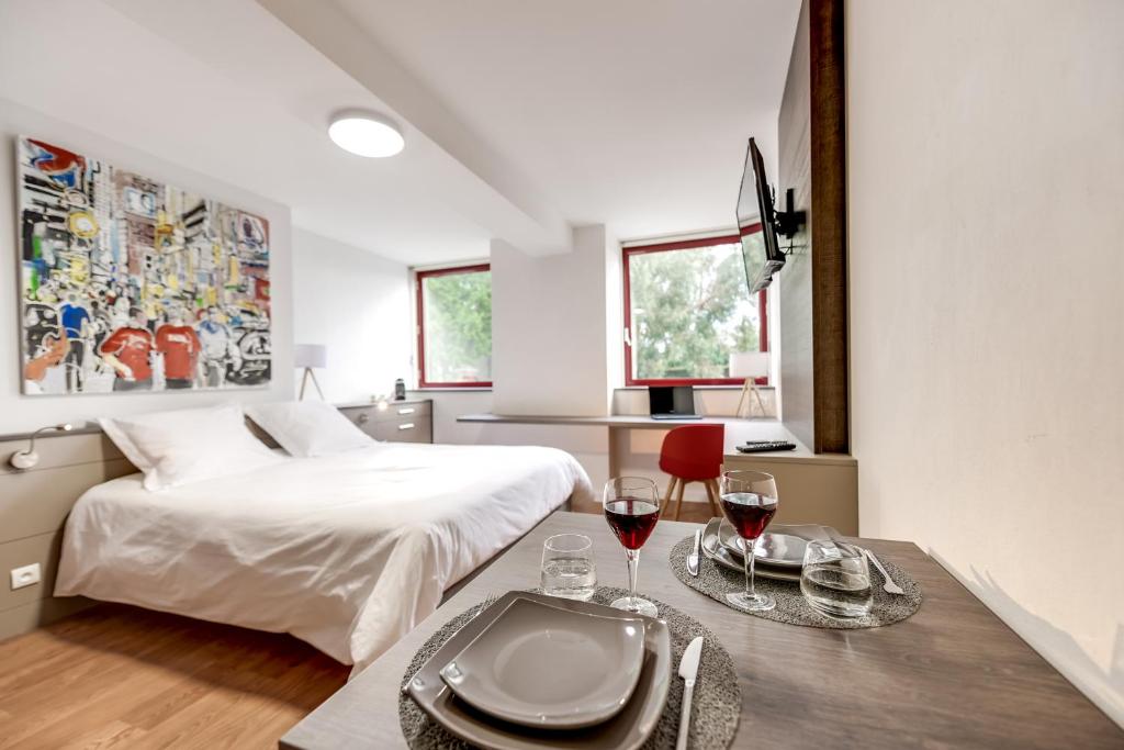 a bedroom with a bed and a table with glasses of wine at Appartement Centre Cholet in Cholet
