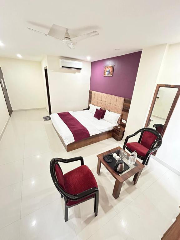 a bedroom with a bed and a table and chairs at Hotel Exotica Haridwar in Rāiwāla