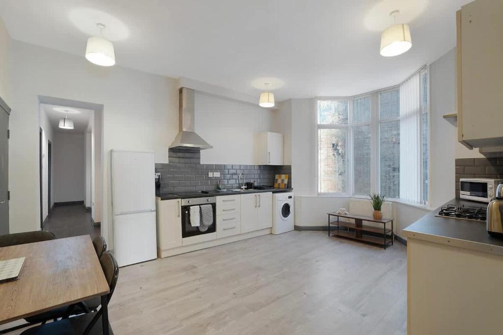 a large kitchen with white appliances and a wooden floor at Spacious 5-Bed Flat in Stockton, Sleeps 9 in Stockton-on-Tees