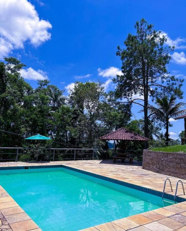 a swimming pool with a picnic table and trees at Pousada Aconchego Shangrilla in Penedo