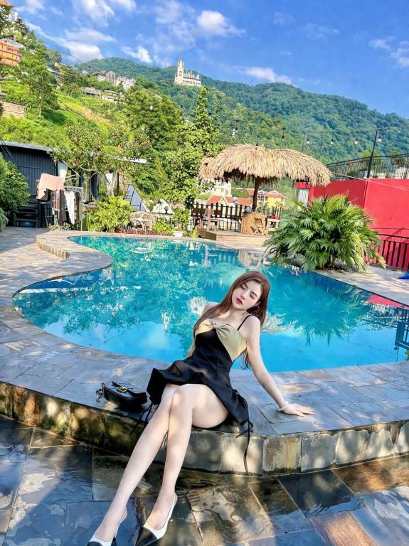 a woman sitting on the edge of a swimming pool at Mây Trắng Homestay in Tam Ðảo
