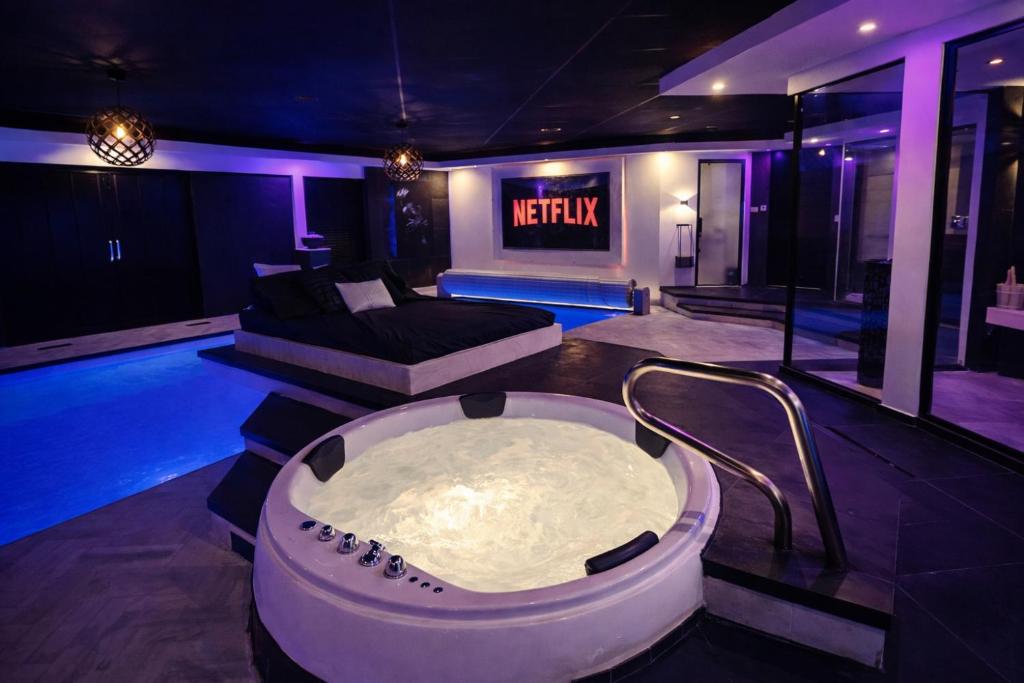 a room with a bath tub and a couch at Bed & Wellness Malina Deluxe zwembad suite in Lelystad