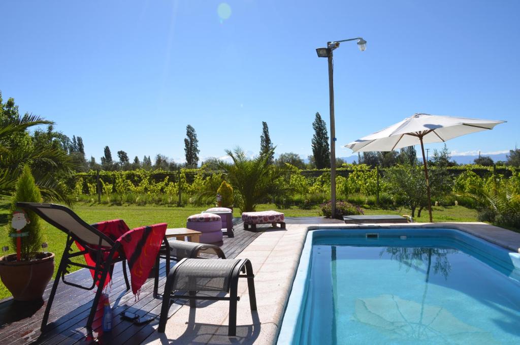 a swimming pool with two chairs and an umbrella at Finca Fisterra in Maipú