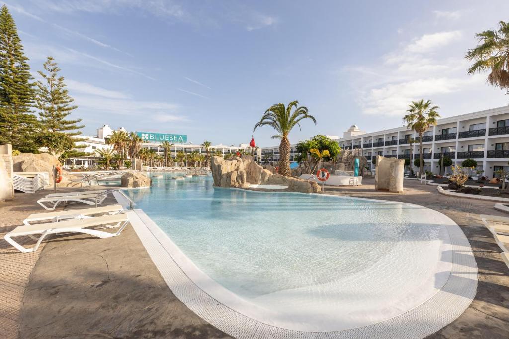 a large swimming pool with two lounge chairs and a resort at BLUESEA Costa Bastian in Costa Teguise