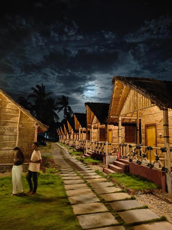 two people walking down a street next to houses at Crazzy Panda Hampi in Hampi