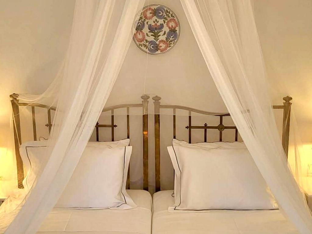 a canopy bed with white pillows and a plate on the wall at Pepromeno Boutique in Agios Dimitrios