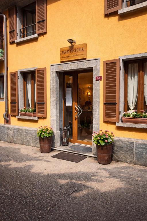 a entrance to a building with two potted plants in front at B&B Osteria Morganti in Someo