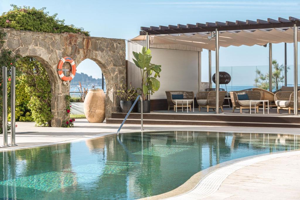 a swimming pool in front of a house with an umbrella at Hotel & Spa Terraza 4 Sup in Roses