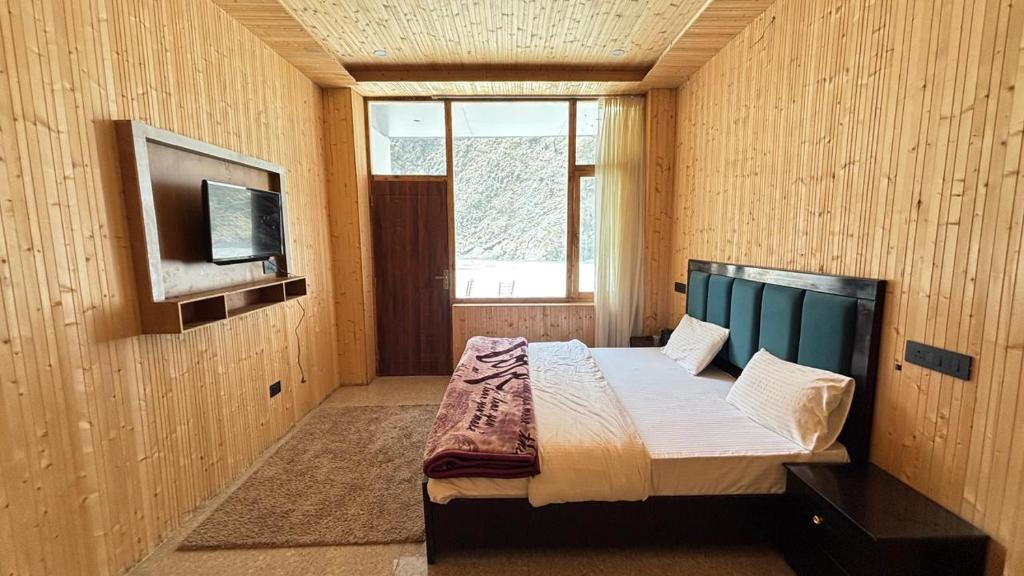 a bedroom with a bed and a tv on the wall at Harsil River Retreat in Harsil
