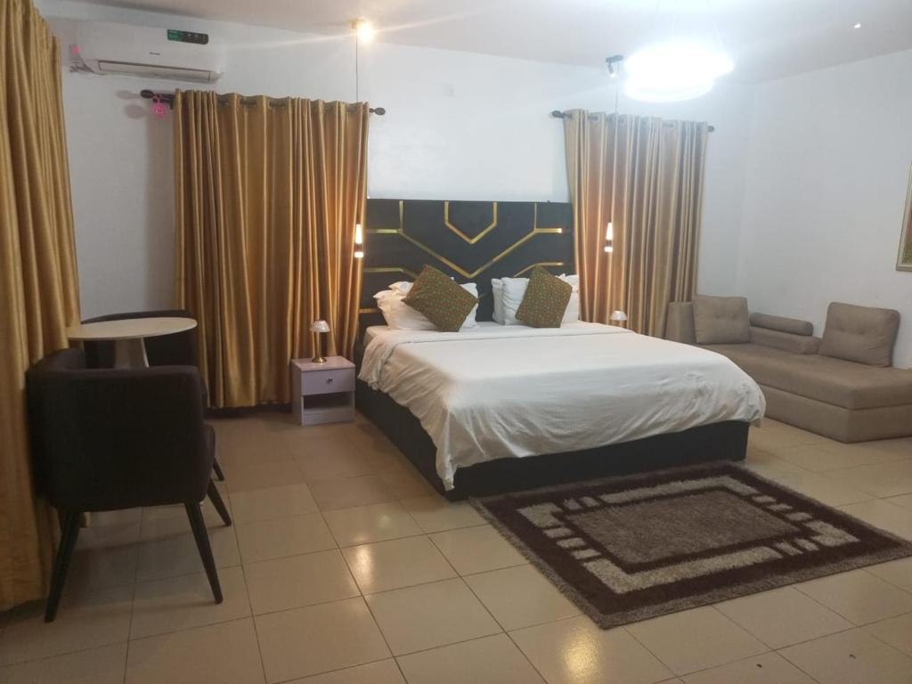a bedroom with a bed and a chair and a couch at Vintage classic suits in Lagos