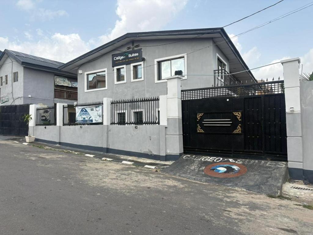 a white house with a gate and a fence at Caligeo Suites I in Ibadan