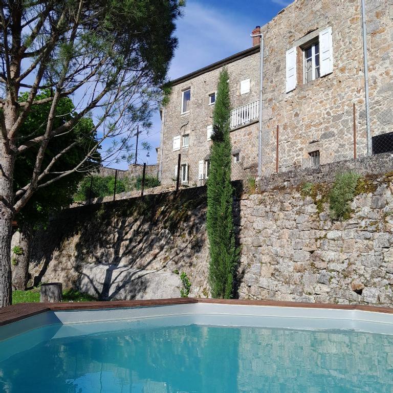 a house with a swimming pool in front of a building at Gîte MANDRA chez gîtes QUE CANTA in Saint-Julien-Vocance